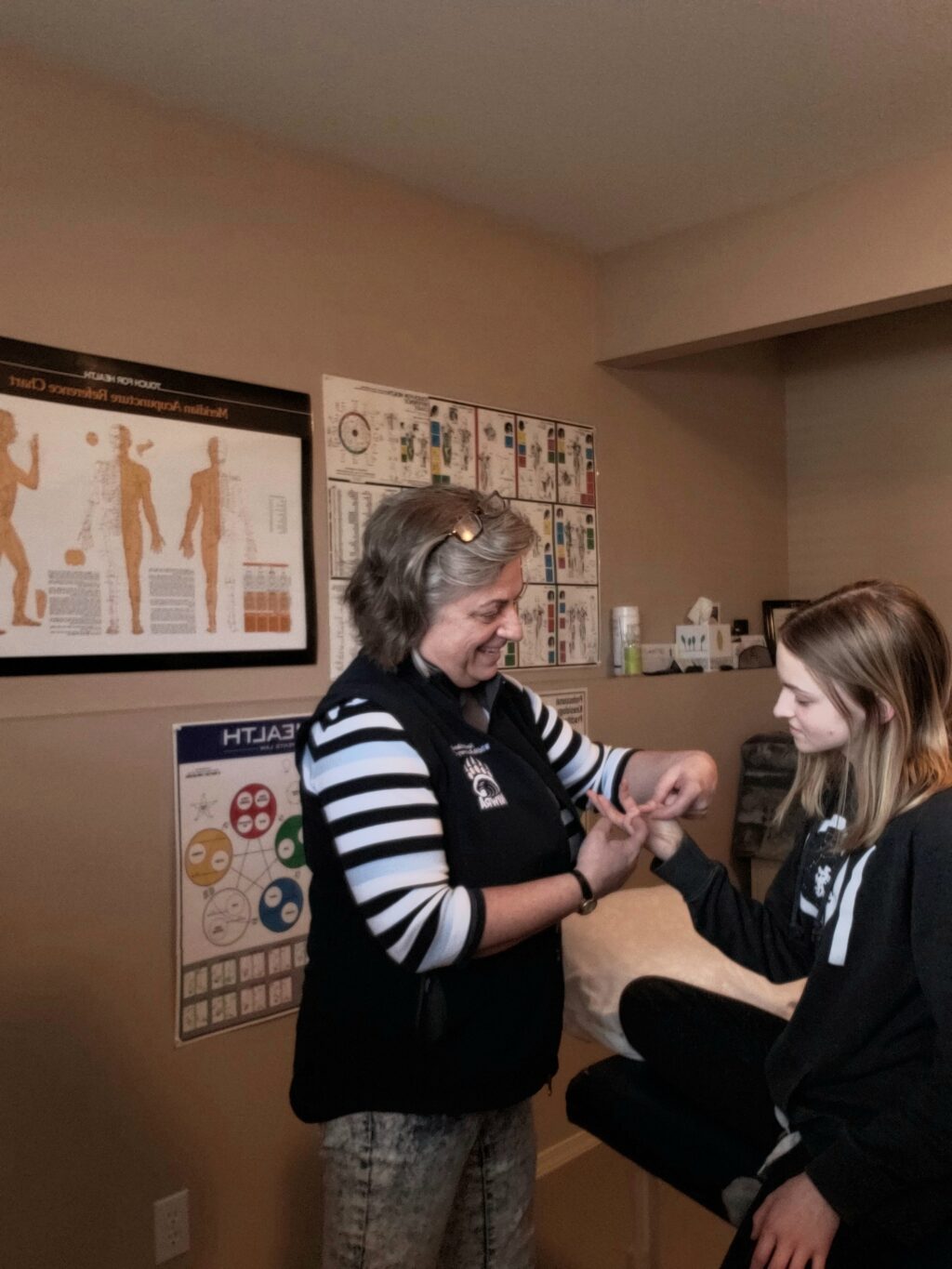 muscle monitoring a client and a facilitator in a room with posters of body systems