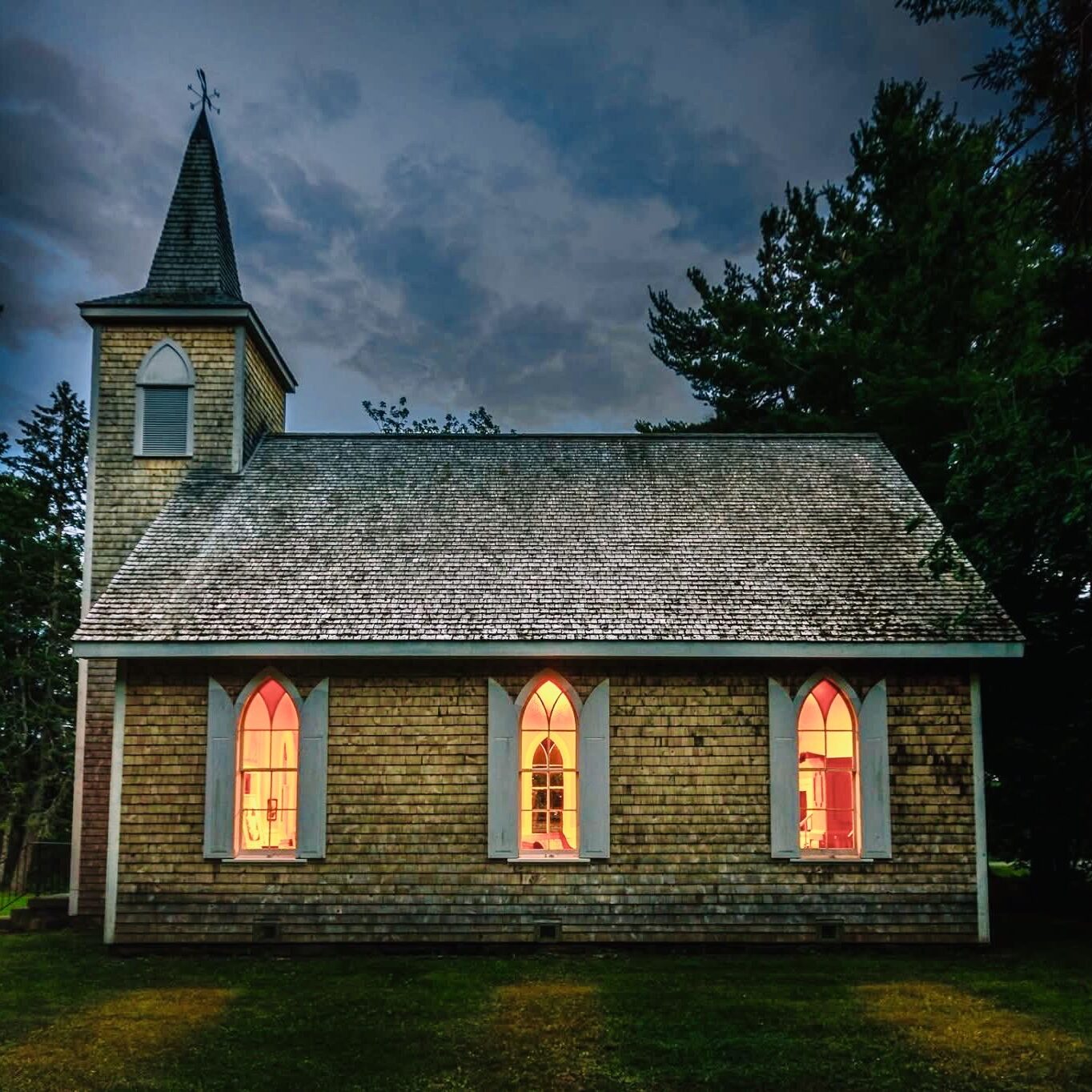 Old church at dusk with lights shining through the window.