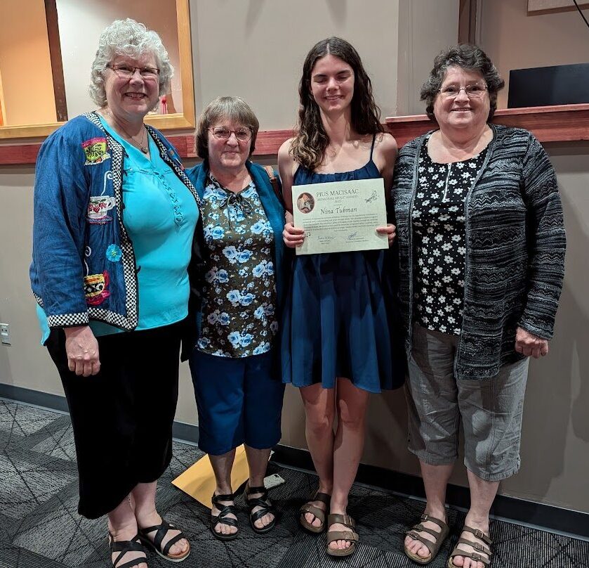four woman standing, one woman receiving an award