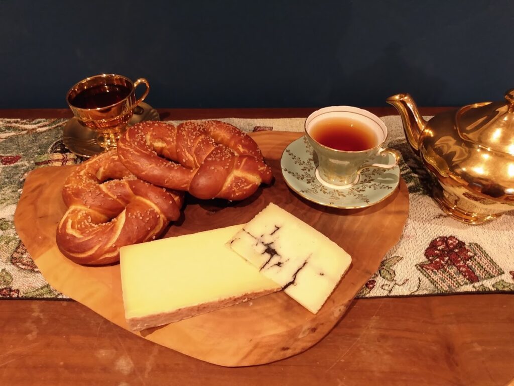 black tea, pretzel and cheese on a wooden platter