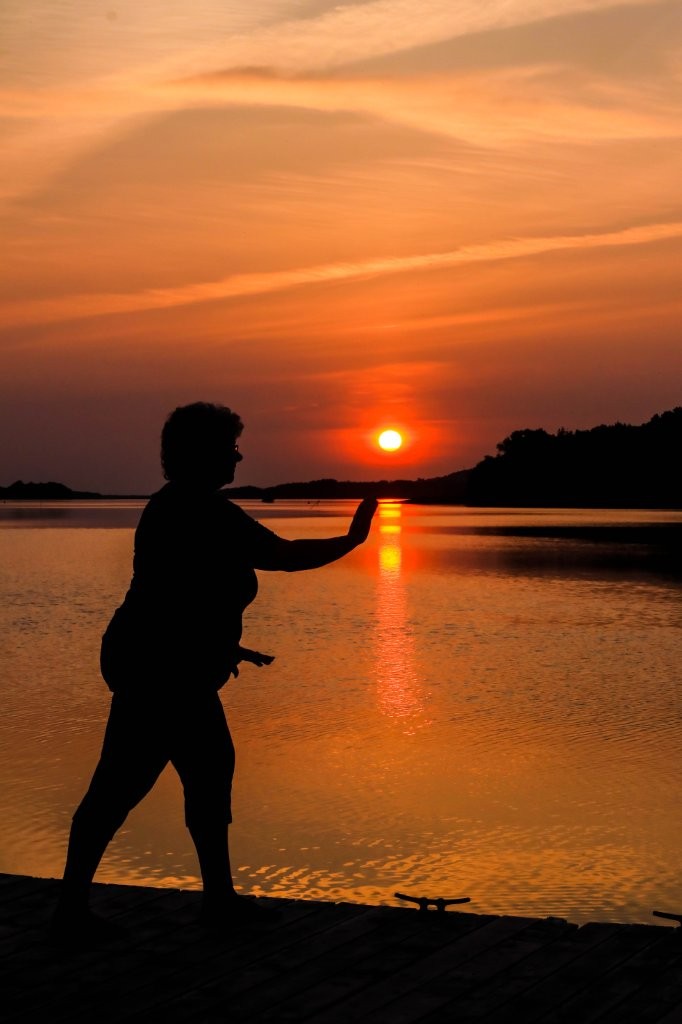 Sunset with a woman doing Tai Chi on the dock near the ocean