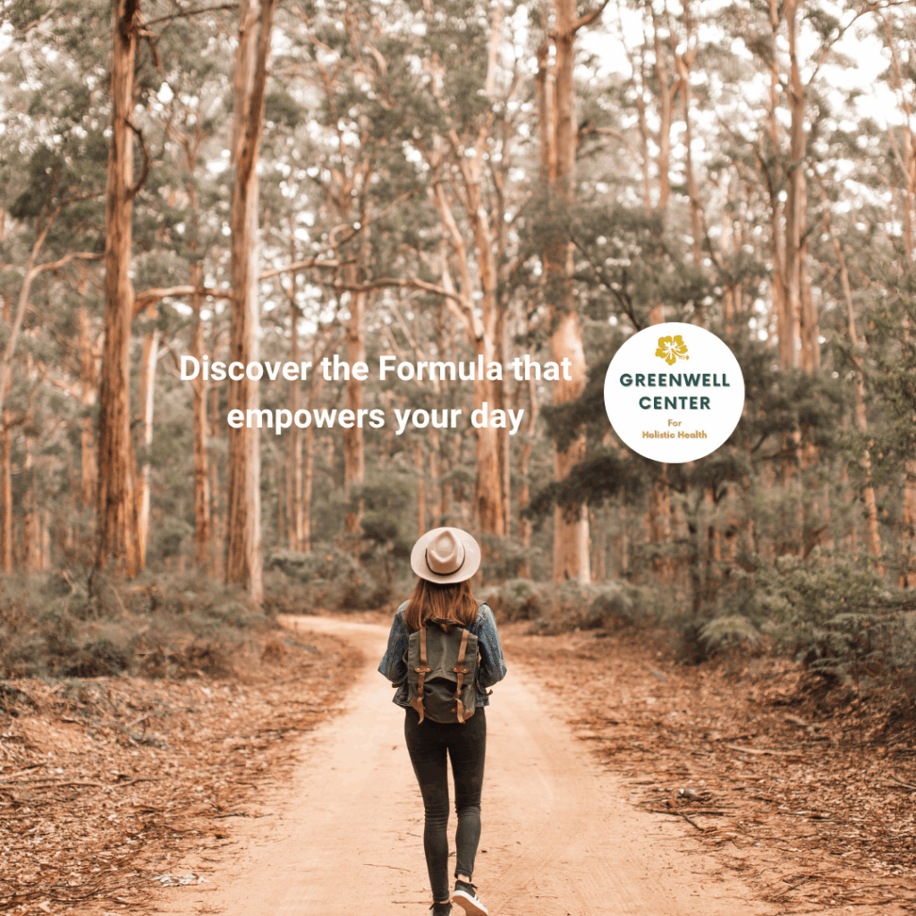 woman with hat on walking down a path in a forested area