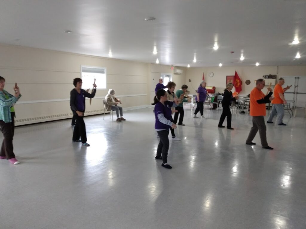 A group of people indoors doing Tai Chi