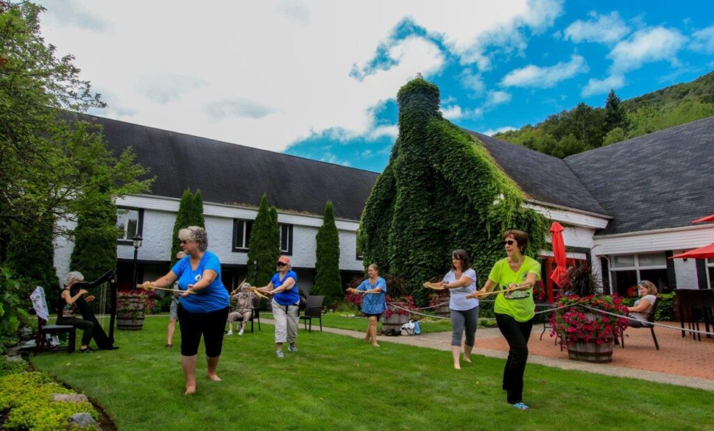 Tai Chi with older adults in a grassy area of a distillery with buildings surrounding.