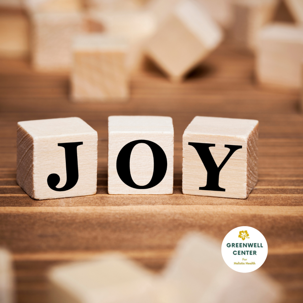 3 wood blocks spell joy on a table with other blocks behind
