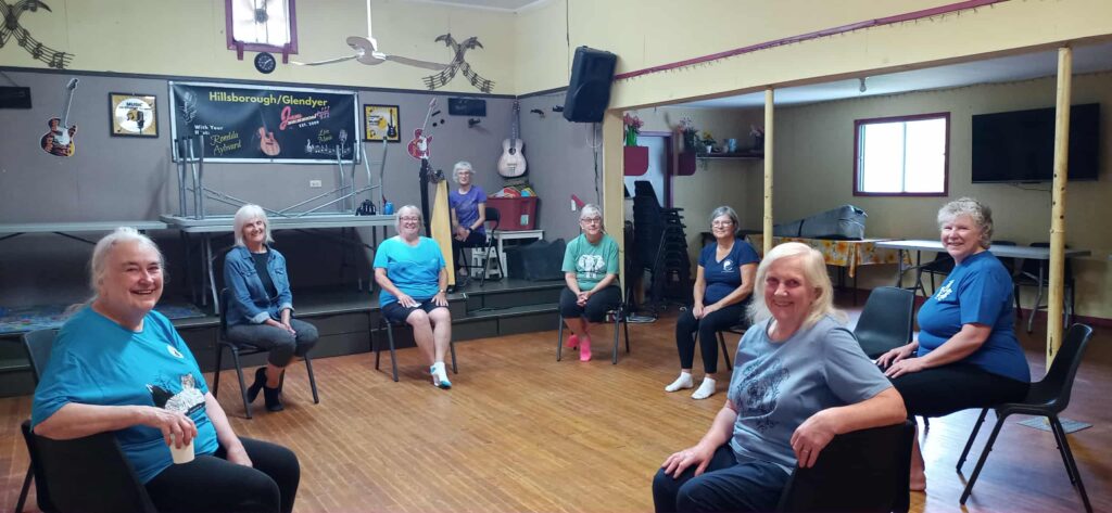 Seated Tai Chi in a hall with senior students and a harpist.